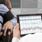 Marathon Grind May Scar the Heart Technician reviews polygraph readings on a tablet beside a seated subject