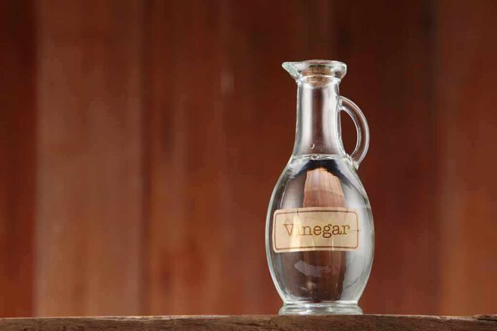 Glass cruet of vinegar on wooden surface