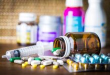 A Guide For Travelling With Chronic Illness Medicine pills and syringe on table with brown bottle
