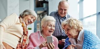 Group of seniors smiling and looking at a smartphone together