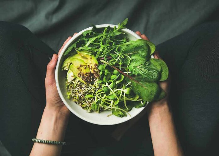 shutterstock_648899398 hands holding a bowl of fresh green salad