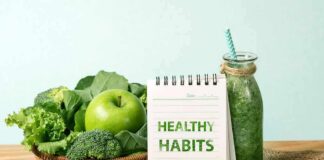 Basket of green vegetables with apple, notebook, and green smoothie