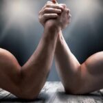 Two muscular arms locked in an arm wrestling match