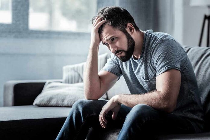 Man sitting on couch with head in hand