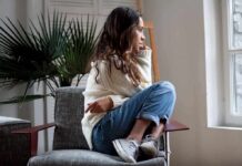 Living Alone Tied To Higher Death Risk Woman sitting curled up on a chair looking out a window