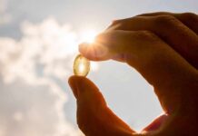 Sun Vitamin Stuns Psoriasis Trials Hand holding a translucent capsule against bright sunlight