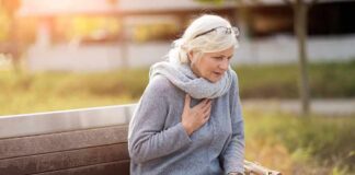Older woman on park bench holding chest