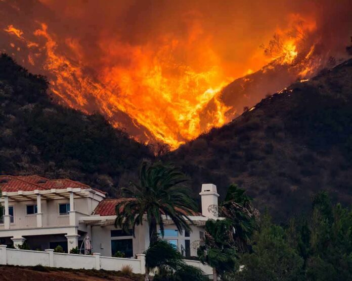 shutterstock_1281996298 Wildfire engulfs hillside behind a suburban house