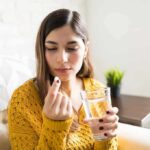 Woman holding a pill and a glass of water