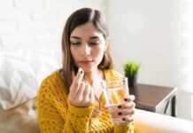 Woman holding a pill and a glass of water