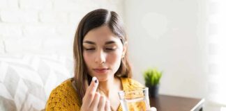 Woman holding a pill and a glass of water