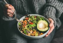 person holding a bowl of salad with avocado
