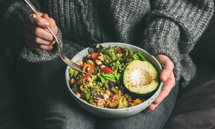 shutterstock_1317602774 person holding a bowl of salad with avocado