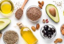 Olive Oil’s Youth Code Assorted healthy fats with avocados, nuts, seeds, olives, and oils on a white background