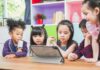 children gathered around a tablet at a table