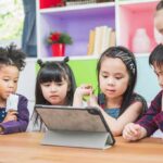 children gathered around a tablet at a table