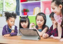 children gathered around a tablet at a table