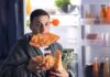 Depression’s Snack Trap – The Hidden Weight Driver man in robe eating pizza at open refrigerator