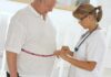 Healthcare worker measuring man's waist with tape