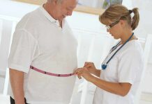 Healthcare worker measuring man's waist with tape