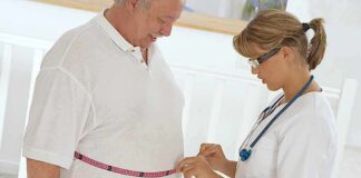 Healthcare worker measuring man's waist with tape