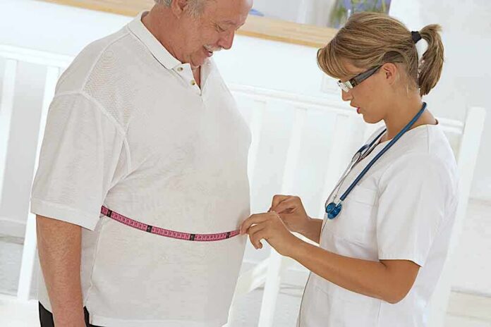 Healthcare worker measuring man's waist with tape