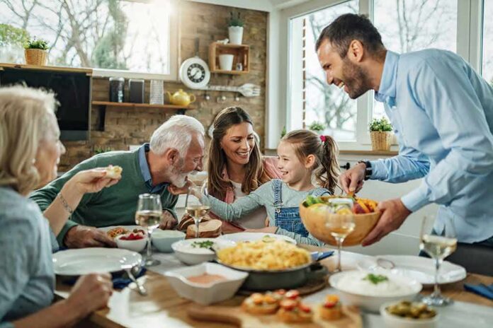 shutterstock_1685806537 Family gathered around a dining table sharing a meal