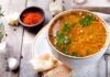 Bowl of lentil soup with herbs on rustic table