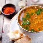 Bowl of lentil soup with herbs on rustic table