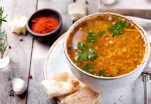 Bowl of lentil soup with herbs on rustic table