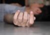 Close-up of a hand on the floor with person lying in background