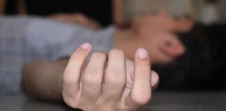 Close-up of a hand on the floor with person lying in background
