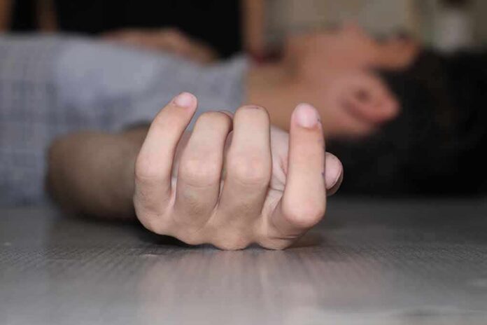 shutterstock_2461280869 Close-up of a hand on the floor with person lying in background