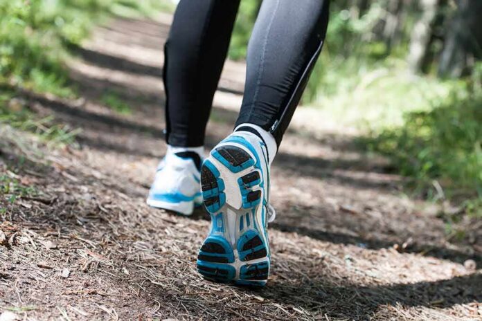 Runner's feet in athletic shoes on a forest trail