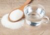 Silent Creatine Mistakes That Wreck Gains Glass of water beside wooden spoon filled with granulated sugar