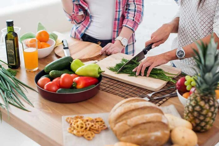 Hands chopping fresh herbs on a cutting board beside assorted produce