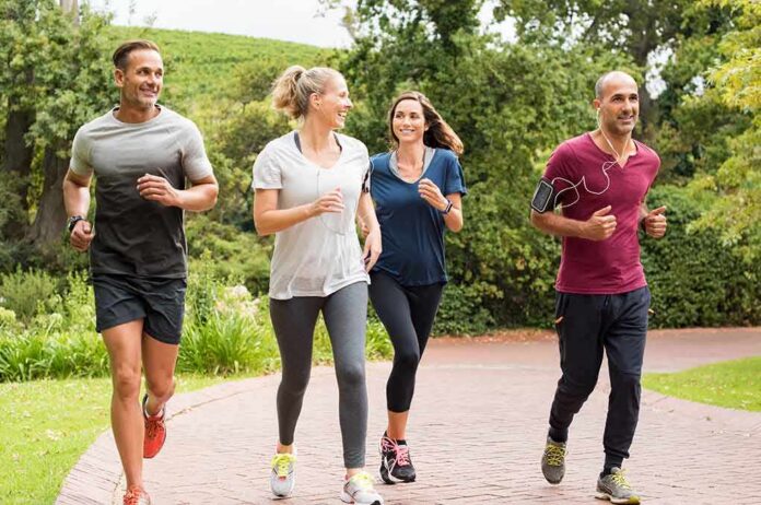Group of four adults jogging on a park path