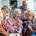 Group of seniors smiling and looking at a smartphone together