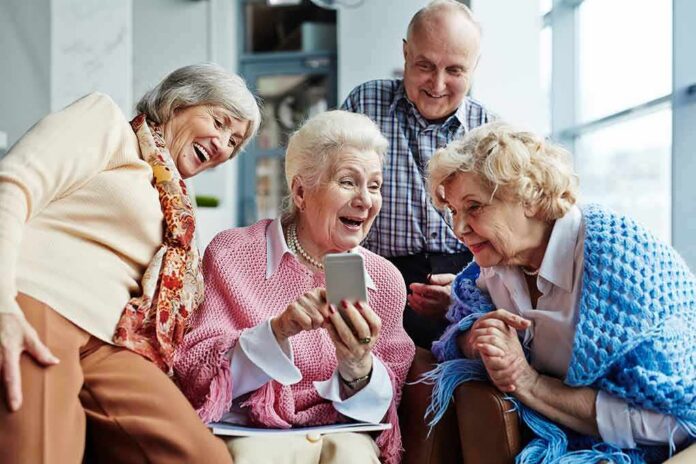 Group of seniors smiling and looking at a smartphone together