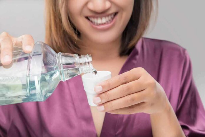 shutterstock_645653464 Person pouring mouthwash into a small cup