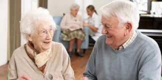 Two seniors smiling while eating a meal together at a table